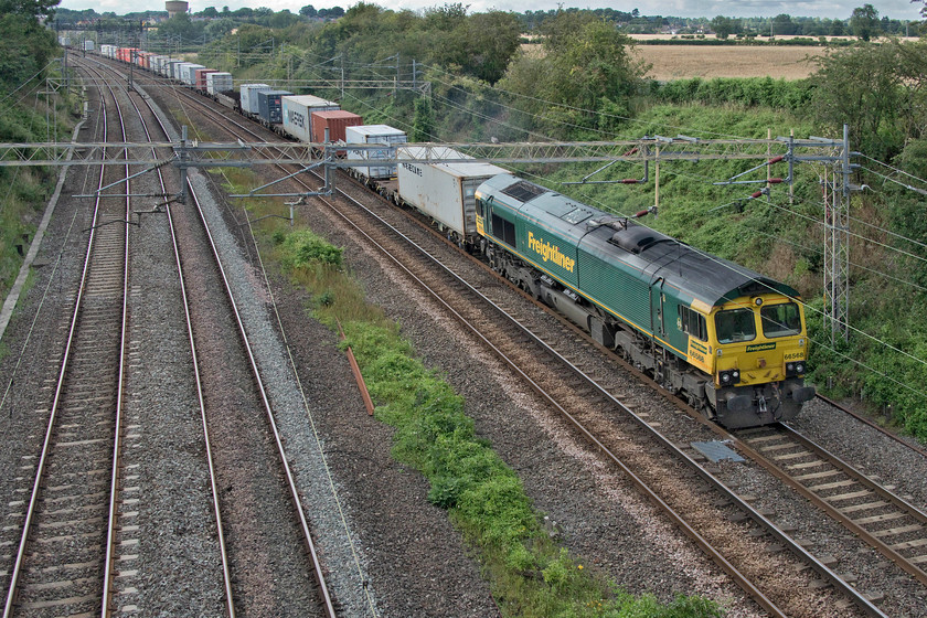 66568, 14.03 Ditton-Felixstowe North (4L92, 95L), Victoria bridge 
 Dull lighting in high summer is always a tricky proposition to the photographer on the lineside. With the monotonous shades of green, the lighting becomes very flat with the situation made worse by a Freightliner Class 66 also in green! 66568 passes Victoria bridge just south of Roade leading the 4L92 14.03 Ditton to Felixstowe Freightliner. 
 Keywords: 66568 14.03 Ditton-Felixstowe North 4L92 Victoria bridge Freightliner