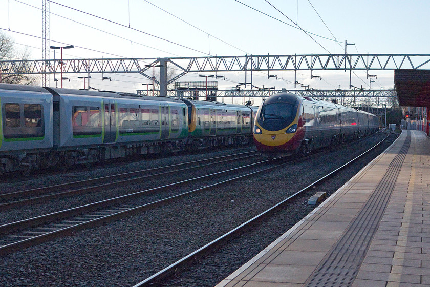 350124 & 350104, LM 16.46 London Euston-Crewe (1U43) & class 390, VT 17.56 Manchester Piccadilly-London Euston (1A61), Stafford station 
 A class 390 takes the centre road through Stafford station working the 17.56 1A61 from Manchester Piccadilly to Euston. It is passing 350124 and 350104 waiting to leave with the 16.46 Euston to Crewe. Despite it being getting on for nearly 19.00 the light is beginning to fade but I have broken the most heinous of photographic rules, namely taking into the light! 
 Keywords: 350124 350104 16.46 London Euston-Crewe 1U43 class 390 17.56 Manchester Piccadilly-London Euston 1A61 Stafford station