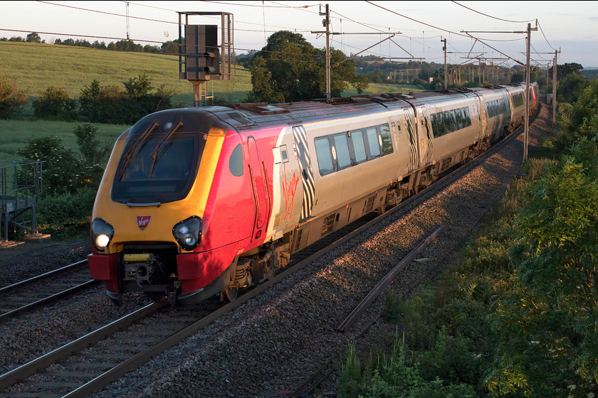 221117 & 221105, 03.57 Barton-under-Needwood-London Euston ECS (5A81), Milton Crossing 
 At a very silly hour in the morning on the longest day, 221117 and 221105 shatter the peace of the Northamptonshire countryside near Blisworth forming the 03.57 Barton-under-Needwood to Euston empty coaching stock working. This daily working runs from the depot near to Burton-on-Trent into New Street and then back south to London to commence its diagram for the day. The sun is just rising behind me but not quite enough to illuminate the front end of the train. However, despite appearances, it was chilly morning for high summer being just six degrees! 
 Keywords: 221117 221105 03.57 Barton-under-Needwood-London Euston ECS 5A81 Milton Crossing