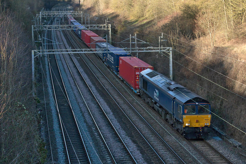 66425, 13.09 DIRFT-Ripple Lane (4L48, 28L), Hyde Road bridge 
 At this time of the year and at this hour of the afternoon, there are very limited opportunities to get decent sunlit images close to my home in Roade. So sometimes one has to embrace the awkwardness imposed on the camera and work with it! Initially, I locked the camera to expose the picture for the background, including some sky in the pre-cropped image. Then back at home, I used Photoshop to cut the chronically underexposed part of the image and create a new layer. I was able to lighten this up sufficiently to create a passable exposure. The lighter background layer needed a little bit of work mainly relating to its colour temperature. After a little more tweaking I then combined the two layers and saved it. The reason for this method is that with digital photography an overexposed initial image is pretty hopeless to work with as it contains virtually no detail whereas an underexposed area does contain lots of data that can be worked with and brought back to life. The image shows 66425 working the 13.09 4L48 Daventry to Ripple Lane service that will later go on to London Gateway. 
 Keywords: 66425,13.09 DIRFT-Ripple Lane 4L48 Hyde Road bridge DRS Freightliner