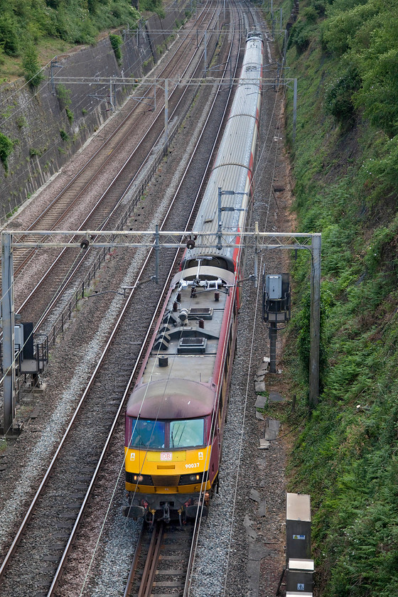 90037 & 90026, 13.32 Wembley Inter City depot-Widnes Transport Technical Centre (5Z90, 4E), Roade cutting 
 It is always on the flip of a coin as to whether special workings that have sufficient speed capabilities will travel via the Northampton loop or via the mainline between Hanslope and Holmorton Junctions. Whilst they may be pathed on either of the routes, on the day control, at the flick of a few switches, will route them the other way so making the choice of a suitable photographic location a bit of a gamble! Roade cutting is a certain spot as both lines are side by side with the Northampton route curving away to the east being on the left in this photograph. Due to go via Northampton, the 5Z90 13.32 Wembley Yard to Widnes Technical Centre (Alstom's facility) is seen here on the fast about to head directly to Rugby making for a pretty poor photograph! This change of route will have disappointed many photographers out to catch this working in the Northampton area and judging by the forum comments there were a number of them! 90037 leads the short set of former LNER Mk.IV stock (12211, 12434, 12310, 11319 and 82201) with repainted 90026 on the rear. 
 Keywords: 90037 90026 13.32 Wembley Inter City depot-Widnes Transport Technical Centre 5Z90 Roade cutting