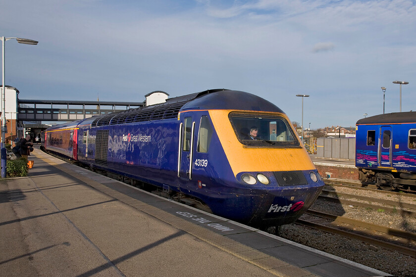 43139, GW 09.36 London Paddington-Cheltenham (1G21), Gloucester station 
 HST power car 43139 'Driver Stan Martin 25 June 1950-6 November 2004' waits at Gloucester station leading the 09.36 Paddington to Cheltenham FGW service. The driver has just changed ends to work the train in its reverse formation for the final few miles of its journey along the former Midland route to the Regency spa town. The HST is occupying approximately half of Gloucester's famous long platform at just over six hundred metres in length, the second-longest in the country. 
 Keywords: 43139 09.36 London Paddington-Cheltenham 1G21 Gloucester station Driver Stan Martin 25 June 1950-6 November 2004