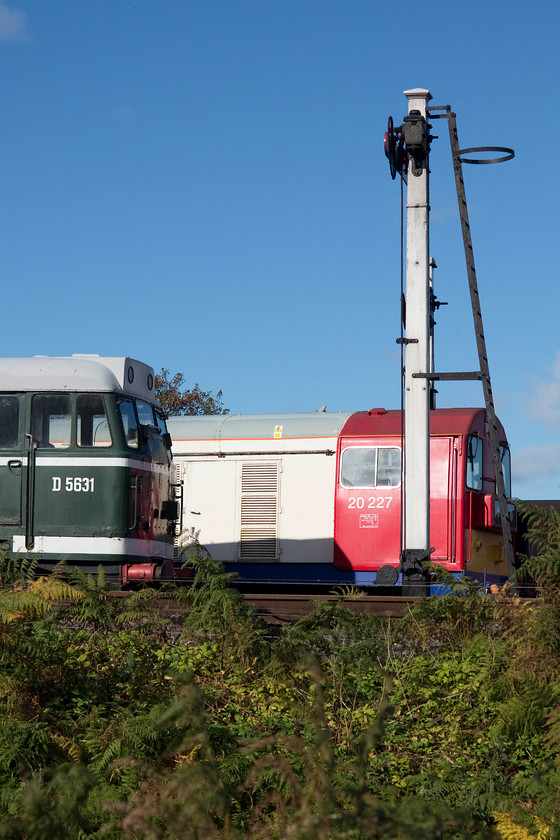 D5631 & 20227, stabled, Weybourne yard 
 Stabled in Weybourne yard, D5631(31207) sits next to 20227. In front of both of them is the M&GN wooden signal post complete with wooden somersault signal arm on top. Whilst D5631 is in an authentic British Railways green livery the class 20 is far from authentic being painted in a London Underground paint scheme. 
 Keywords: D5631 20227 stabled, Weybourne yard