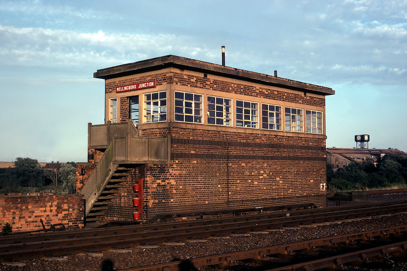 Wellingborough Junction signal box (LMS, 1943) 
 Wellingborough Junction signal box is the signalling equivalent of a WD Austerity locomotive, indeed, it was built during the same year, 1943. But, despite its somewhat austere appearance it was built to ARP specification including such features as 14" thick brick walls, a flat reinforced concrete roof of 12" thickness and metal window frames in an effort to reduce the risk of fire. It replaced a smaller box located a few yards north of this location. It carries its original London Midland & Scottish Railway Company post-1935 design name board. The box continued in use for another three years from when this picture was taken closing in November 1983 and was demolished some three years after that. In the background is the water tower of the British Leyland foundry; a town landmark for many years even after its closure by the nationalised car maker in 1981. In a nod to its heritage today, the site is home to the Leyland Trading Estate. 
 Keywords: Wellingborough Junction signal box