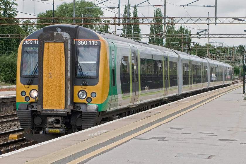 350119, 11.33 Birmingham New Street-London Euston (1W12), Northampton station 
 Our train to London drifts into Northampton station. 350119 is working the 11.33 Birmingham New Street to London Euston 1W12 service. Despite the cloud it is high summer and notice the fly encrusted connecting doors of the Desiro. 
 Keywords: 350119 11.33 Birmingham New Street-London Euston 1W12 Northampton station London Midland Desiro