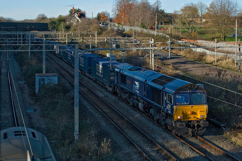 66421, 13.37 DIRFT-Tilbury FLT (4L48, RT), site of Roade station 
 66421 just catches some early afternoon sunshine on its nose as it emerges from Roade cutting leading the 4L48 13.37 DIRFT (Daventry) to Tilbury 'Tesco Express'. Notice the up Pendolino just going out of shot to the bottom left of the image. 
 Keywords: 66421 13.37 DIRFT-Tilbury FLT 4L48 site of Roade station DRS Tesco Express