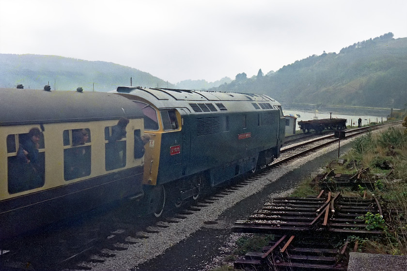 D1013, 16.45 Kingswear-Paington, KIngswear SX884514 
 D1013 'Western Ranger' brings the curtain down working the final train from Kingswear to Paignton service of the day and of its stay at the Torbay and Devon Railway. Along with D1062, both locomotives were to leave the railway and move to a new home on the Severn Valley. Here, the train is seen leaving Kingswear from a position atop a small concrete hut just outside of the station with the Dart Estuary in the background. 
 Keywords: D1013 16.45 Kingswear-Paington KIngswear SX884514