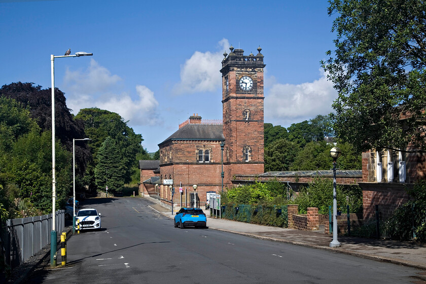 Station drive & frontage, Ulverston station 
 This is the second attempt that I have had to replicate my 1985 photograph of the station drive leading to Ulverston station. The reason was that in my first attempt, I parked the car on the wrong side of the road, see.... https://www.ontheupfast.com/p/21936chg/30061915084/entrance-frontage-ulverston-station Not making the same mistake again I have parked my car on the right adjacent to the first lampost up. When I scan and upload the image from 1985 I will provide a link here that will show my parents' carmine red Triumph Dolomite 1500 (RLJ 767X) rather than my Holborn blue MG4 as seen here. 
 Keywords: Station drive frontage Ulverston station