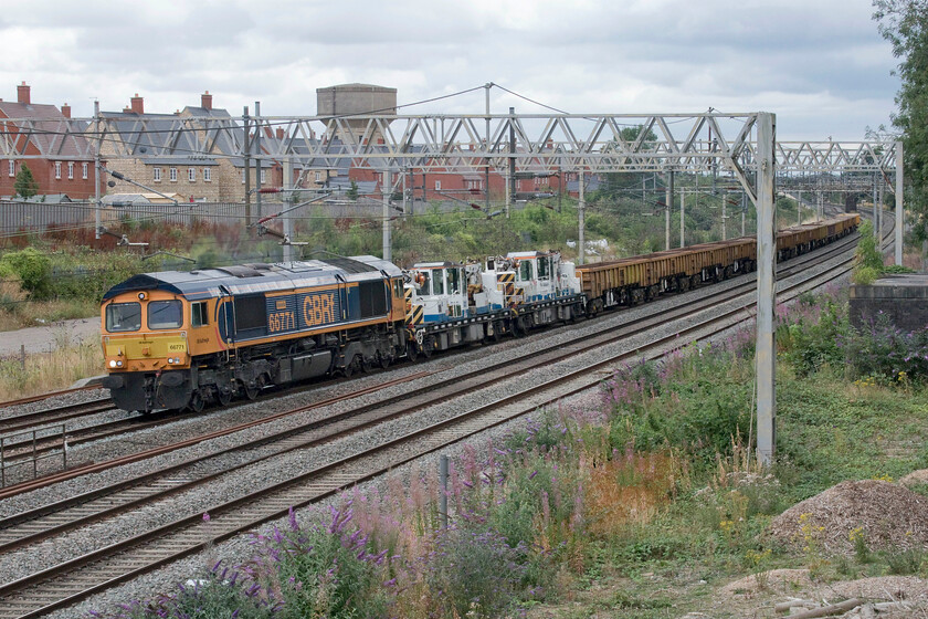 66771, 07.00 Denbigh Hall South-Bescot (7G51, 7E), site of Roade station 
 66771 'Amanda' leads the 7G51 07.00 Denbigh Hall (Bletchley) to Bescot infrastructure train past the site of Roade's former station. The train is composed of a pair of twin jib cranes and a rake of JNA ballast wagons with varying amounts of material loaded in them. 
 Keywords: 66771 07.00 Denbigh Hall South-Bescot 7G51 site of Roade station GBRf Amanda