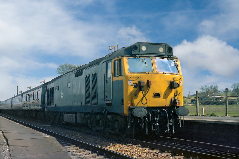 50029, unidentified down working, Bedwyn station 
 Having come to a stop at the station, 50029 pauses with an unidentified down working awaiting the right away from Bedwyn station in Wiltshire. This was an unscheduled stop and the guard can be seen peering out the Mk. I BG wondering what is causing the delay. 
 Keywords: 50029 down working, Bedwyn station