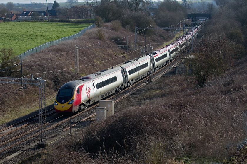 390156, VT 11.07 London Euston-Liverpool Lime Street (1F15, 7L), A45 Weedon bypass bridge 
 390156 'Stockport 170' passes through Weedon with the 11.07 Euston to Liverpool Lime Street. This is a new photographic position that has become available with the opening of the new Weedon bypass. The bridge that carried the old A45, that blighted the village, is seen in the distance. This was also the spot that Weedon station was located that closed on 15.09.58. The slightly raised section of land parallel to the line where the boxes are situated carried the ex L & NW line that linked the WCML to Leamington Spa via Daventry and Southam. 
 Keywords: 390156 11.07 London Euston-Liverpool Lime Street 1F15 A45 Weedon bypass bridge