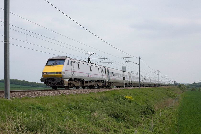 91121, GR 15.30 London King's Cross-Edinburgh Waverley (1S23), Frinkley Lane crossing SK906436 
 91121 and its set of East Coast liveried stock blends almost seamlessly with the grey sky as it heads north past Frinkley Lane crossing near the former Barkston Junction. Photographs like this on grey days with very flat skies need a fair amount of work in Photoshop to make a reasonable finished product. Like is so often the case and as described in stage two of https://www.ontheupfast.com/technical-notes the sky is selected and worked on before the rest of the image is tackled. 
 Keywords: 91121 15.30 London King's Cross-Edinburgh Waverley 1S23 Frinkley Lane crossing SK906436 East Coast