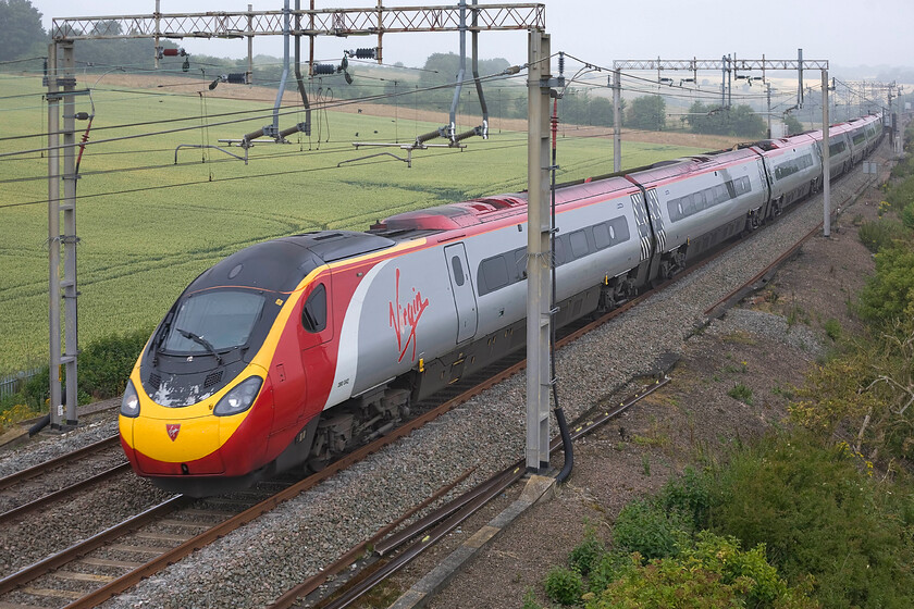 390042, VT 06.35 Manchester Piccadilly-London Euston (1A06), Blisworth SP735539 
 390042 'City of Bangor/Dinas Bangor' looks a little shabby around the front end as it works the 06.35 Manchester Piccadilly to London Euston near to Blisworth on the Weedon loop line. Note that the dense fog from just a relatively short time ago is beginning to lift as the fields in the background begin to come into view. 
 Keywords: 390042 06.35 Manchester Piccadilly-London Euston 1A06 Blisworth SP735539 Virgin Pendolino City of Bangor Dinas Bangor