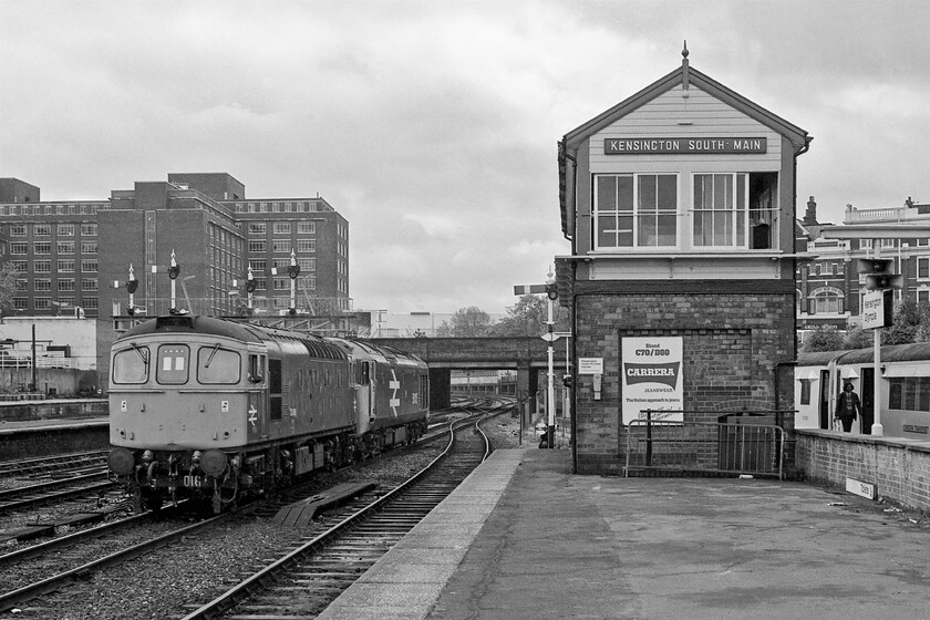 33016 & 50015, unidentified LEs, Kensington Olympia station 
 As we were alighting from our tube train at Kensington Olympia station the through signals were pulled off and this duo appeared around the curve in the distance and under Kensington High Street bridge. I am not at all sure as to why large logo 50015 'Valiant' was being dragged by 33016 but my suspicion is that it was being taken for attention back to Old Oak Common following use on the L&SWR Waterloo to Exeter route. The superb and rather grand Kensington South Main signal box controlled signalling to the south end of the station with North Main at the other end that also controlled access to the Motorail terminal. Kensington was a strange mixture GWR lower quadrant signalling controlled by an LMS box. The box was closed in the early 1990s when the semaphore signalling was abolished but the empty box survived until the autumn of 1993. Notice the R-Stock tube train sitting at the adjacent platform that will soon be returning the very short distance to Earl's Court. 
 Keywords: 33016 50015 unidentified light engines Kensington Olympia station Valiant