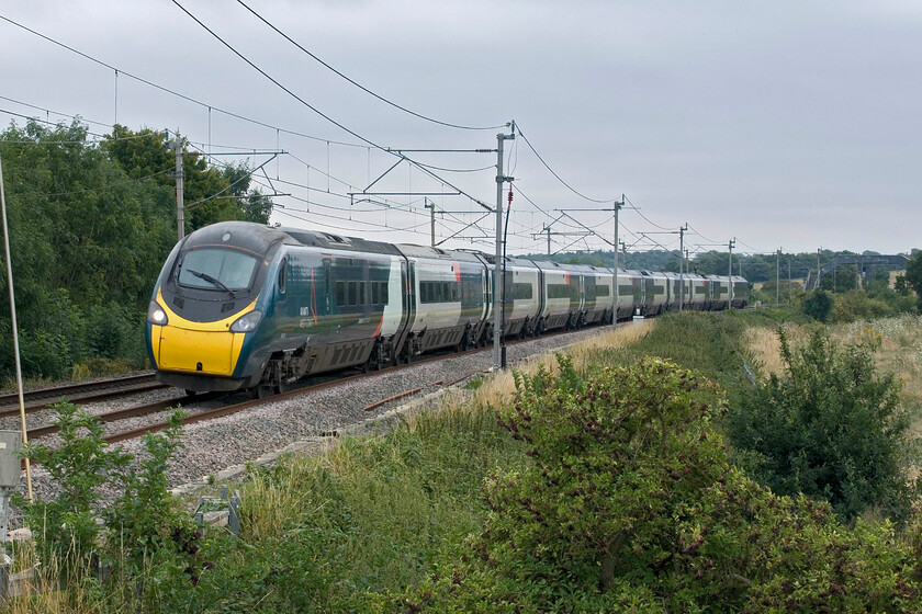 390126, VT 12.30 London Euston-Glasgow Central (1S63, 1L), Blisworth 
 Avanti's 390126 passes Blisworth on the Weedon loop line (the 'old route') working the 12.30 Euston to Glasgow Anglo Scottish Express. The flat and dull weather of this August day does not bring anything to the quality of this image. 
 Keywords: 390126 12.30 London Euston-Glasgow Central 1S63 Blisworth Avanti West Coast Pendolino