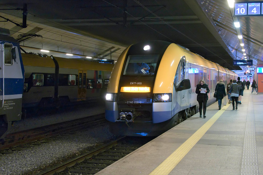 EN77-005, 17.22 Krakw Glwny-Tarnw (KML33421), Krakw Glwny station 
 Inside the somewhat dark interior of Krakw's Glny station, Actus 2 EN77-005 waits to leave with the 17.22 evening commuter train to Tarnw. It looks like the driver is about to get his journey details or updates on the route from the guard who is just approaching the cab, papers in hand. These EN77 units, of which five are operated in this area by Maopolskie province, were roomy and looked comfortable with passengers sitting at two levels within the coaches. Notice in this image the large folding mirrors that are a feature of all Polish trains. 
 Keywords: EN77-005 17.22 Krakw Glwny-Tarnw KML33421 Krakw Glwny station Acatus 2 PESA Małopolskie province