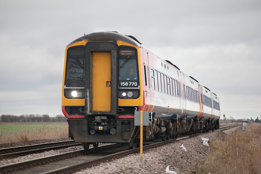 158770 & 158783, EM 10.47 Norwich-Liverpool Lime Street (1R82, 1L), Three Horse Shoes no.1 level crossing 
 158770 and 158783 work the East Midlands' 10.47 Norwich to Liverpool service. The train is seen approaching Three Horse Shores no.1 level crossing about two miles west of March. It was a particularly bleak and windy day out on the Fens. Indeed, as I was waiting to take this picture a couple of cyclists were trudging up the road towards me walking their bikes as the north westerly wind had defeated them! I was quite pleased to drive the short distance and get into the relative protection of the town of March! 
 Keywords: 158770 158783 10.47 Norwich-Liverpool Lime Street 1R82 Three Horse Shoes no.3 level crossing