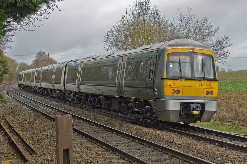 168004, CH 08.15 Birmingham Moor Street-London Marylebone (1H25, 1E), Claydon crossing SP451498 
 Despite the seemingly bright weather it was, in fact, pouring with rain! The 08.15 Birmingham Moor Street to Marylebone passes near the north Oxfordshire village of Claydon worked by Chiltern turbo unit 168004. There used to be an occupation level crossing at this location, the post of which can be seen to the left, but there is now just a footpath crossing which is busy with dog walkers and rail enthusiasts alike! 
 Keywords: 168004 08.15 Birmingham Moor Street-London Marylebone 1H25 Claydon crossing SP451498 Chiltern Turbo