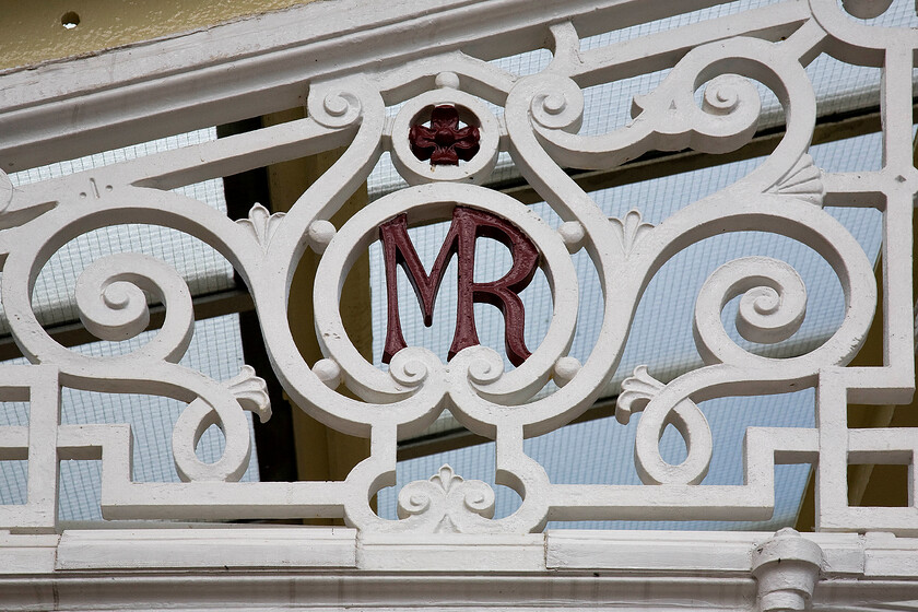 Midland Railway insignia, Hellifield station 
 The cast iron work that characterises Hellifield station is absolutely superb and there is plenty of it! Here, supporting the glazed roof is a section that includes a Midland Railway roundel very cleverly cast uniting the two letters. Notice the wire mesh glass panels that make up the glazed roof. These will be replacements for the original roof, one wonders what type of glass the Victorians will have installed when they built the station back in 1880? 
 Keywords: Midland Railway insignia Hellifield station