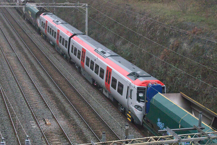 197014, 10.35 Crewe Basford Hall-Wolverton Centre Sidings (6Q98, 32L), Hyde Road bridge 
 A close-up of a brand new Class 197 unit wearing its unbranded TfW livery as it passes through Roade cutting taken from Hyde Road bridge. On the week that this photograph was taken the first of these Spanish-built CAF units had just entered service with TfW. This example was difficult to identify as it appeared to have no numbering either bodyside or on the front. However, a close examination of the white sheet of A4 paper sellotaped to the interior of the cab window revealed it to be 197014. Out of sight on the front Freightliner's 66531 was towing the ensemble as the 6Q98 10.35 Crewe Basford Hall to Wolverton Works. 
 Keywords: 197014 10.35 Crewe Basford Hall-Wolverton Centre Sidings 6Q98 Hyde Road bridge Freightliner TfW