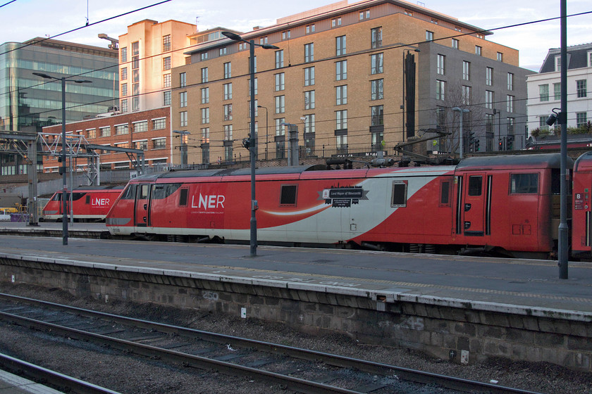 91122, GR 16.00 London King`s Cross-Edinburgh (1S24, 6L) & 91130, GR 16.05 London King`s Cross-Leeds (1D21, RT), London King`s Cross station 
 As it's late December, the sun has already gone sufficiently low in the London sky to be putting King's Cross into full shadow and it's only 15.30! Two class 91s wait to head north with services that have yet to go over to Azuma operation. Nearest the camera is 91130 'Lord Mayor of Newcastle' that will leave at 16.05 with the 1D21 to Leeds. Behind it on platform zero is 91126 that will leave five minutes earlier with the 16.00 to Edinburgh. This background is familiar at King's Cross with the low brick building to the far left featuring in many of my contemporary images, see .....https://www.ontheupfast.com/v/photos/21936chg/25366392204/x40101-stabled-london-kings-cross This building on York Road, named York Central, has recently been converted into rather expensive flats. 
 Keywords: 91122 16.00 London King`s Cross-Edinburgh 1S24 91130 16.05 London King`s Cross-Leeds 1D21 London King`s Cross stationLNER Lord Mayor of Newcastle