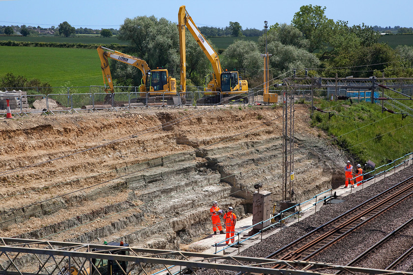 H&S team at work, Ashton Road bridge work site 
 Following the tragic death of a trackside worker employed by Amco Giffen (working for Network Rail) on 08.04.20 this worksite just south of Roade on the WCML has remained shut. This hi-viz clad team were actually white-collar staff and seemed to be inspecting and making a lot of notes on clipboards in addition to taking many photographs. I am sure that once the various agencies have done all their work and that the site is passed then the operation to stabilise the embankments can continue. However, in all of this, one must not forget that a man lost his life at this site and is survived by a family including children. Our thoughts must go out to them at this very difficult time. 
 Keywords: H&S team at work Ashton Road bridge work site