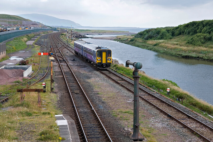 153360 & 153304, NT 13.32 Lancaster-Carlisle, Sellafield station 
 153360 and 153304 approach Sellafield station working Northern's 13.32 Lancaster to Carlisle service. Hopefully, this train is relaitevely empty and therefore able to offer plenty of room to the masses gathered on the platform as seen in the previous picture. Notice the vintage water column in the centre foreground that was presumably fed by the substantial water tower at the far end of the station behind me. Also, notice the DRS Class 37 and 20 to the extreme left used to haul the flask trains to and from the vast repossessing facility off to the left 
 Keywords: 153360 153304 13.32 Lancaster-Carlisle Sellafield station Northern