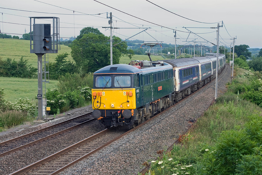 87002, CS 20.44 Inverness, 21.43 Aberdeen & 19.50 Fort William-London Euston sleeper (1M16), Milton crossing 
 Due to issues with a Class 90, Caledonian Sleeper had to use 87002 'Royal Sovereign' to work a northbound sleeper service on 23.06.15. This meant that the vintage AC electric was somewhat isolated out of position in Scotland and unable to undertake its ecs duties from Wembley to Euston. Rather than run it as a highly inefficient light engine operation it was utilised on the 1M16 up Highland Sleeper. After checking the internet I found that it was indeed leading the train so I popped out from home to see the train passing a rather grey Milton crossing between Roade and Blisworth. Notice that the 87 is in its smart new Caledonian Sleeper livery with branding but that the Mk. III stock is still in the old First Group livery who relinquished the franchise three months previously. 
 Keywords: 87002 20.44 Inverness 21.43 Aberdeen 19.50 Fort William-London Euston sleeper 1M16 Milton crossing Caledonian Sleeper Royal Sovereign