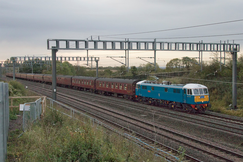 86259, outward leg of The Cumbrian Mountain Express, 07.12 London Euston-Carlisle (1Z86, 15L), Ashton Road bridge 
 On a very dull and miserable Saturday morning 86259 'Les Ross/Peter Pan' approaches Roade leading the outward leg of 'The Cumbrian Mountain Express' railtour running with its usual headcode of 1Z86. This is a new spot recently opened up after the embankment next to Ashton Road bridge, just south of Roade, has been repaired and reinforced with rock armour. Following the completion of the work, the palisade fencing has been reinstated meaning that the use of a ladder or poking the camera through the gap with the flip-out screen extended is required in order to get a reasonable photograph. 
 Keywords: 86259 The Cumbrian Mountain Express, 07.12 London Euston-Carlisle 1Z86 Ashton Road bridge