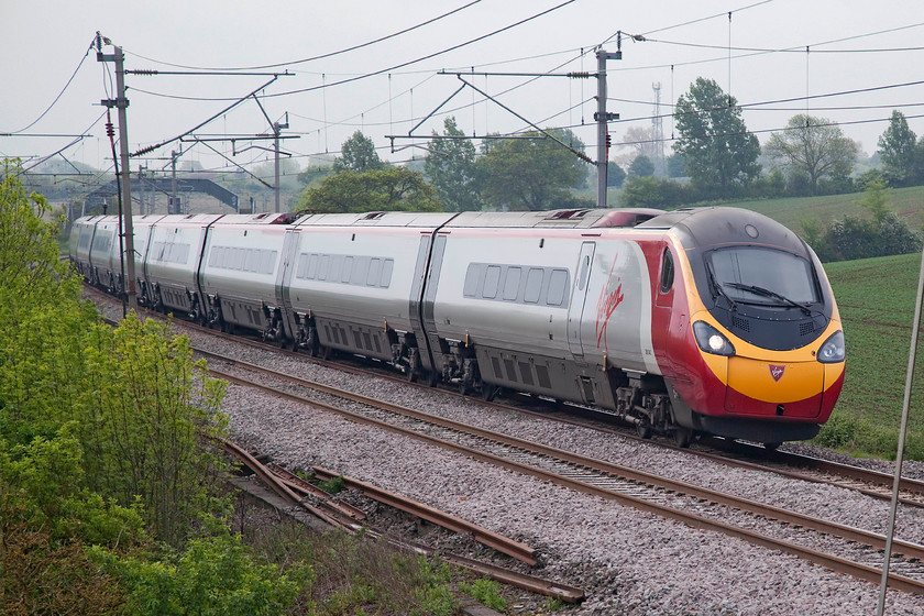 390042, VT 07.23 London Euston-Birmingham New Street (9G05, 1L), Blisworth 
 A particularly dull and overcast morning did not dent my need to get out and see an '86' out on the mainline! Control let a sequence of three down Pendolinos pass it before giving it the road with the veteran electric and its train kept waiting a Hanslope Junction some seven miles south of this spot. The second of the priority workings is 390042 on the 07.28 Euston to Birmingham. 
 Keywords: 390042 9G05 Blisworth