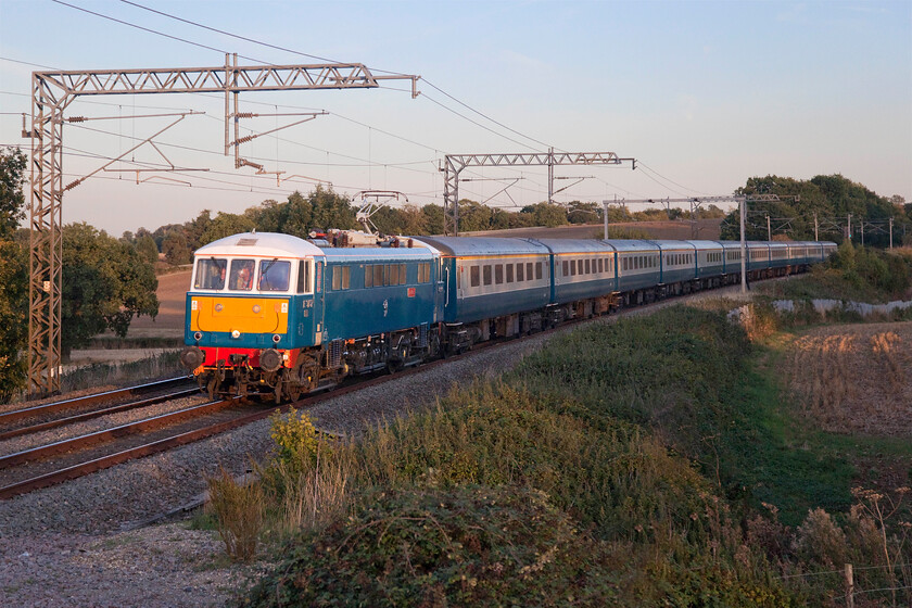 86259, 17.51 London Euston-Lancaster (1Z87, 2E), Milton crossing 
 The shot that almost did not quite work as well as it has actually tuned out! The returning 17.51 Euston to Lancaster WCR relief service on behalf of the hapless Avanti West Coast is seen catching the very last of the fast-setting sun. Some three minutes later as I was returning to the car it had dropped below the horizon which would have made the photograph very tricky. 86259 'Les Ross/Peter Pan' hauling the super set of matching stock had to be halted at Bletchley following its centre screen being smashed just north of Linslade with all other northbound services also halted in the area for an inspection to take place. The travelling fitter joined the cab at Bletchley and can be seen sitting behind the broken screen with his hands pressed against it; not ideal! Obviously, the incident did not affect the train too much as it arrived two minutes early into Lancaster. Trouble is, where does one source a centre screen for a locomotive that is over fifty years old, I suppose a quick trawl around Basford Hall may well secure one! 
 Keywords: 86259 17.51 London Euston-Lancaster 1Z87 Milton crossing AL^ Les Ross Peter Pan