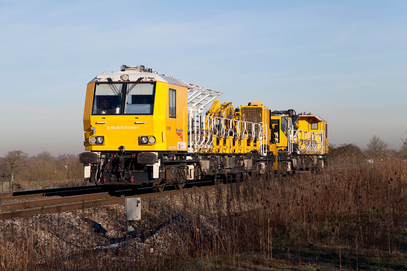 DR76906 & DR76905 10.00 Swindon Transfer-Swindon Transfer (6H09), South Marston foot crossing SU196870 
 Seen passing one of South Marston's foot crossings is a pair of the Windhoff contraptions that have been specifically constructed to 'build' the OHLE on the GWML. Theses two units are DR76906 and DR76905 and are doing a massive round-robin trip as the 6H09 10.00 Swindon to Swindon via Chippenham, Westbury, the Berks. and Hants. line, Reading and back again; quite the purpose of this run I am not at all sure. However, these hugely expensive and purpose built units intended to mechanise and speed up the electrification process have not worked as intended so it could be linked to work to improve their reliability? 
 Keywords: DR76906 DR76905 10.00 Swindon Transfer-Swindon Transfer 6H09 South Marston foot crossing SU196870