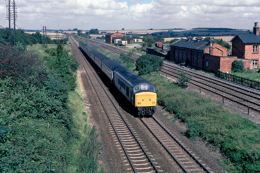 45141, 07.58 Leeds-London St. Pancras (1M14), site of Irchester station 
 45141 gathers speed on its assault of Sharnbrook bank from the north. It is seen passing the site of Irchester station leading the 1M14 07.58 Leeds to St. Pancras service. ETH Class 45s (45/1 subclass) were the mainstay of MML services for many years supplemented by Class 47s until June 1987. Irchester station closed on 07.03.60 twenty years prior to this photograph being taken but nothing remains of the platforms with just some buildings and goods shed giving the game away. The station building was located on the bridge I am standing on with access straight down on to the island platform from it. 
 Keywords: 45141, 07.58 Leeds-London St. Pancras site of Irchester station 1M14