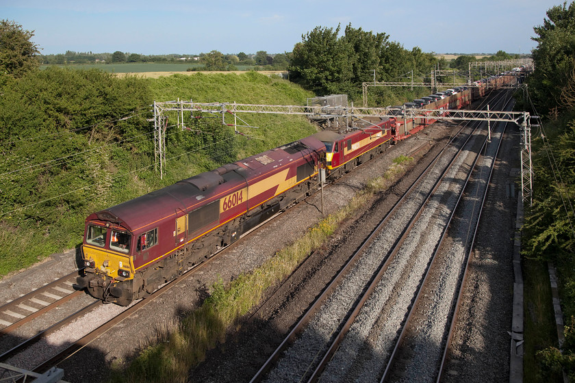 66014 & 90028, 13.58 Dagenham-Mossend (6X77), Victoria Bridge 
 The daily 13.58 Dagenham to Mossend 'Fords', as it is known, passes Victoria Bridge between Northampton and Milton Keynes, in brilliant summer evening light. This working is double-headed by 66014 and 90028. Close examination of the image reveals that the pantograph on the class 90 is lowered so it was not under-power. It could have failed or it could simply be a logistical locomotive move? Further study also shows my shadow over the bridge of the parapet right down in the left hand corner. 
 Keywords: 66014 90028 13.58 Dagenham-Mossend 6X77 Victoria Bridge