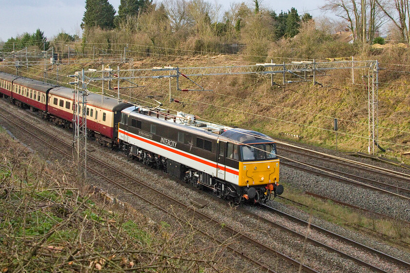 86101, outward leg of the London to Settle & Carlisle Railway, 06.06 London Euston-Carlisle (1Z61, RT), Victoria bridge 
 Making use of a new photographic position as a result of recent embankment clearance 86101 Sir William Stanier FRS leads the outward leg of the 1Z61 London to Settle & Carlisle Railway charter past Victoria bridge just south of Roade. It makes a change to see the LSL-owned ac electric rather than the more common 86259 and also that it has been pathed via Northampton thus on the slow line. Due to a partial camera malfunction involving the touch screen, I have managed to crop the heritage Mk. I stock and 47514 (in actuality being 47853) bringing up the rear. 
 Keywords: 86101 London to Settle & Carlisle Railway 06.06 London Euston-Carlisle 1Z61 Victoria bridge Sir William Stanier FRS AL6 Intercity swallow