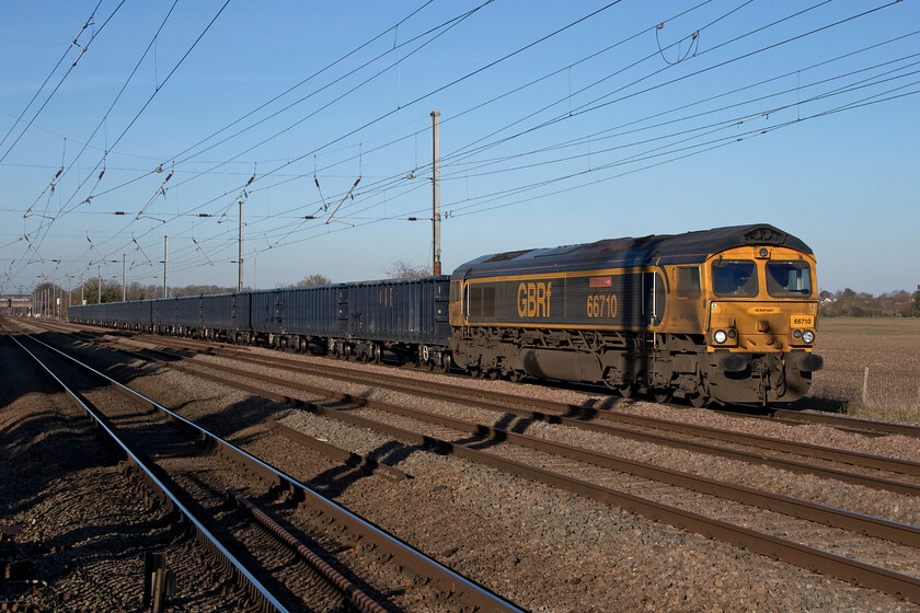 66710, 13.09 Peterborough North Yard-Angerstein Wharf (6O57, 46L), Holme Green crossing TL192426 
 Just before heading back to the van and for the drive back to Northampton I waited for only the second freight of the day that I observed on the southern ECML. The very late running 13.09 Peterborough North Yard to Angerstein Wharf 6O57 empty spoil wagons passes south at Holme Green crossing led by GBRf's 66710 'Phil Packer'. Glancing down the rake of new JNA-X box wagons finds them devoid of any vandalism for the moment at least but I wonder for how long they will remain this way? 
 Keywords: 66710 13.09 Peterborough North Yard-Angerstein Wharf 6O57 Holme Green crossing TL192426 GBRf Phil Packer