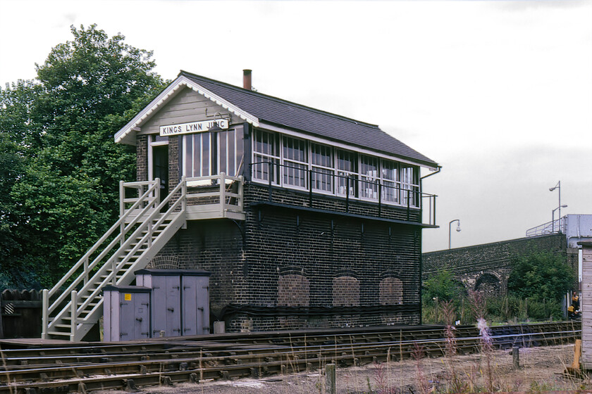 King's Lynn Junction signal box (GE, c.1880) 
 Kings Lynn Junction signal box was once a busy place to work controlling a complex network of lines as well as the level crossing with Tennyson Road where the line ran into the station, the busy yard and shed. In quieter times with just the Derham line open as far as Middleton Towers (freight only) and fewer trains operating on the lines south to Cambridge the Great Eastern box dating from c.1880 is seen complete with its wooden nameboard. The unusually robust brick footbridge can just be seen that gave pedestrians a chance to cross the line when the gates were shut on the busy level crossing. This footbridge was removed when the electrification wires were installed with the box still extant at the time of writing in 2023. 
 Keywords: King's Lynn Junction signal box GE Great Eastern railway