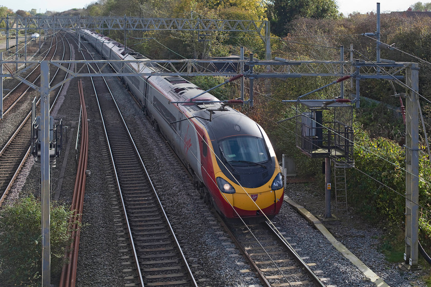 390123, VT 12.00 London Euston-Manchester Piccadilly (1H23), site of Roade station 
 Heading north past the site of the now closed Roade station, 390123 forms the 12.00 Euston to Manchester Piccadilly. Where the trees are growing directly above the train was the location of Roade's large LNWR signal box. 
 Keywords: 390123 12.00 London Euston-Manchester Piccadilly 1H23 site of Roade station