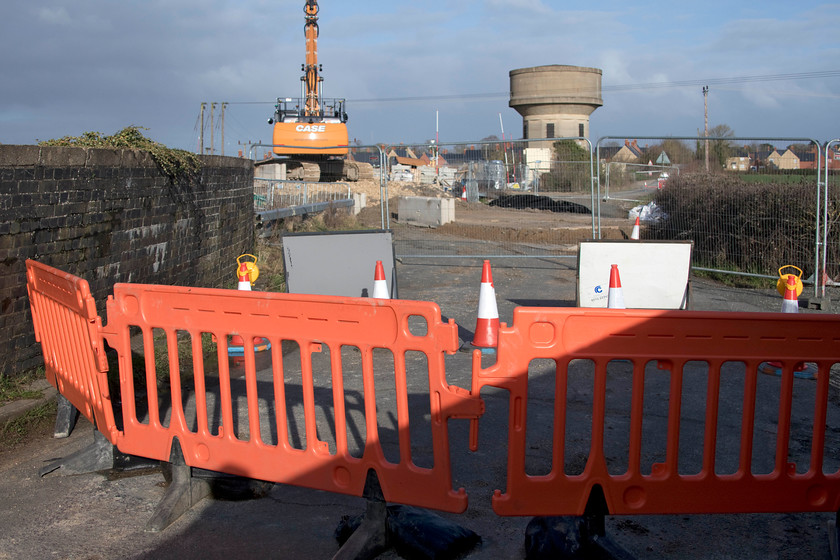 Road closure & embankment reinforcement work, Ashton Road bridge 
 Ashton Roade bridge just south of Roade has been closed for over a month now affording access to the contractors (Amco Giffen) to reinforce the embankments to the north side of the bridge. With the closure due to expire next Sunday (a week's time) I am not sure if the work will be completed. In this view looking towards Roade, with one of its two water towers dominating the scene, the temporary access road that has been constructed can clearly be seen. With a week left of the closure, I thought that a team may well have been at work today on what was, after all, a quiet Sunday with very little railway traffic given the COVID emergency timetable in operation. 
 Keywords: Road closure & embankment reinforcement work Ashton Road bridge Roade