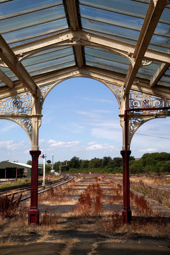 Hellifield station 
 The wonderful wrought ironwork at Hellifield station was erected by the Midland Railway and opened in June 1880. The architect was the renowned Charles Trubshaw who was responsible for many other railway buildings including one of my local stations, Kettering. Notice the Midland Railway insignia in the iron work. Unfortunately, at the other end of the station the canopy is supported by some acrow props as it is fracturing and putting the structural integrity at risk. As the station is Grade II listed I am sure that the work will be undertaken and that it will be repaired sympathetically! 
 Keywords: Hellifield station