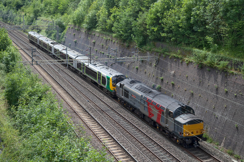 37 611 & 350256, 08.55 Northampton EMD-Long Marston (5Q94) (Via Weedon Loop, run round at Bletchley CS), Roade Cutting 
 37611'Pegasus' tows 350256 through Roade Cutting on the down fast meaning that it is going to take the Weedon loop line to Rugby and beyond. The 08.55 Northampton EMD to Long Marston is on the down fast (and running very late by this stage) as it had gone south to Bletchley where the 37 ran round to take the unit north again. This strange movement was because the Northampton line was closed north of the town. Incidentally, the class 350 was being taken to Long Marston for corrosion repairs, a process that every class 350 was going through over the period of a few months. 
 Keywords: 37 611 & 350 256, 08.55 Northampton EMD-Long Marston (5Q94) (Via Weedon Loop, run round at Bletchley CS), Roade Cutting