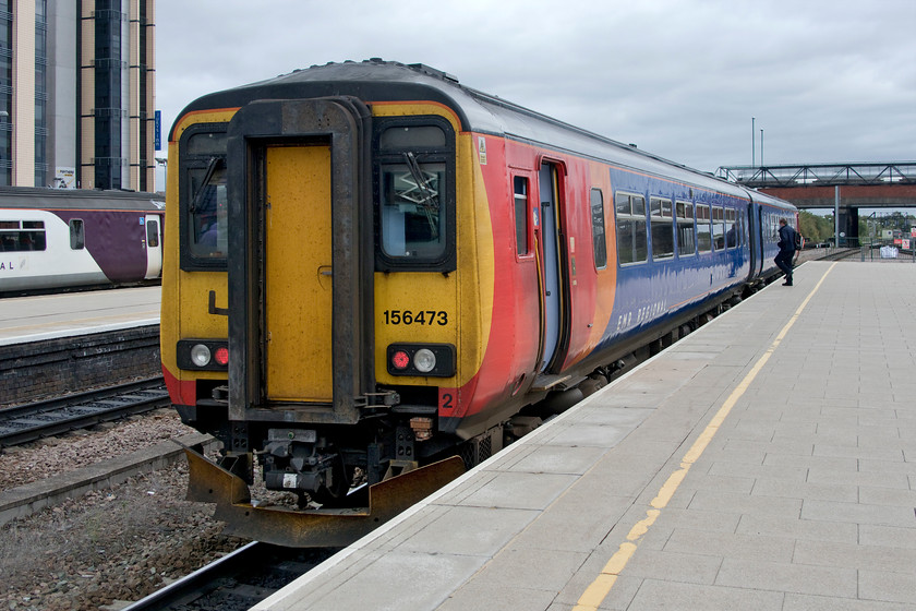 156473, EM 10.37 Matlock-Newark Castle, (2N31, 1E), Nottingham station 
 156473 stands at the very end of Nottingham's distant (from the concourse) platform 4b. The East Midlands Railway unit was working the 10.37 Matlock to Newark Castle 2N31 service that Andy and I had just travelled on from Derby. The relief driver is seen just about to climb aboard the train during its generous seven minutes' dwell time. 
 Keywords: 156473 EMR 10.37 Matlock-Newark Castle 2N31 Nottingham station East Midlands Railway Super Sprinter