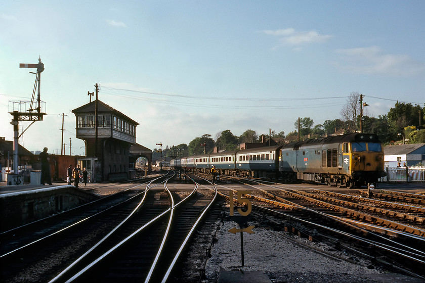 50041, 16.25 London Paddington-Plymouth (1B14), Exeter St. David's station 
 I think that I was somewhat overcome by events on this superb summer evening at Exeter St. David's as the arrival of 50041 'Bulwark' excited me enough to take four images of it on the same train using slide film. The cost of this to me as a schoolboy would have been significant! The first photograph shows it entering the station, leading the 1B14 16.25 Paddington to Plymouth over Red Cow level crossing. Of interest is the way that the light has illuminated the view through the old goods shed beyond the signal box. Also, notice the crossing keeper standing confidently in the centre of the up line supervising proceedings and pedestrians already milling about to the side waiting to cross. My travelling companion, Graham, is seen on the end of the platform under the up starter bracket signal. 
 Keywords: 50041 16.25 London Paddington-Plymouth 1B14 Exeter St. David's station Bulwark.jpg