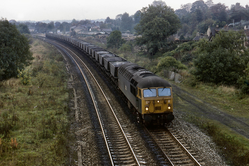 56026, down empty merry-go-round, Duffield A6 road bridge 
 As 40069 headed round the corner, 56026 appeared from the south with another train of MGR wagons no doubt heading off to some local coal mine before the Conservative Government allowed Ian MacGregor to close it down. Duffield's sawmill, located just north of the station can be seen in the distance on the right, it has no been replaced by the somewhat inevitable housing estate. 56026 was one of the last members of the class to be built by Electroputere in Craiova, Romania. It was just over two years old when this picture was taken and survived in service until July 1996 giving it a working life of a mere nineteen years. 
 Keywords: 56026 empty merry-go-round Duffield A6 road bridge