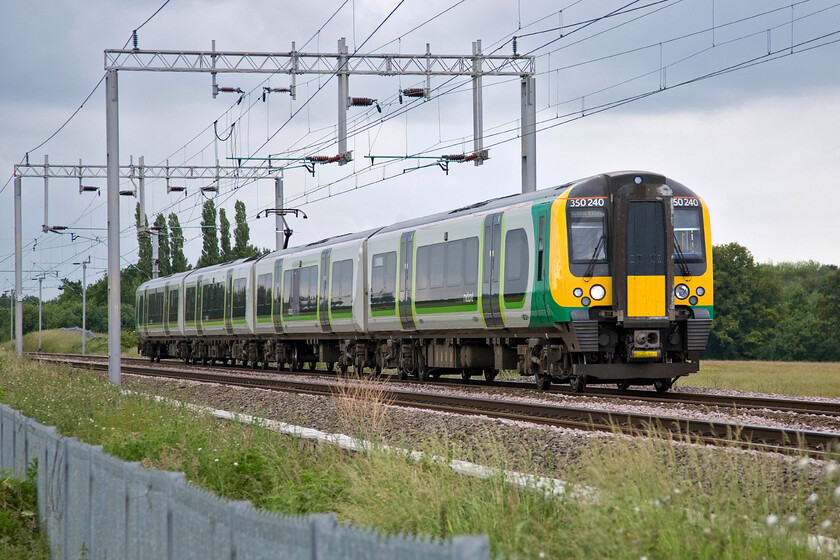 2. 350240, LM 15.54 Birmingham New Street-London Euston (2Y16), Wilson's crossing 
 The recent installation of the dreaded palisade fencing here at Wilson's crossing just north of Northampton has had one benefit, namely the clearance of all of the lineside vegetation that now affords this view of up services. London Midland's 350240 brings the 15.54 Birmingham to Euston service southwards slowing for its stop at Northampton some mile and a half away. 
 Keywords: 350240 15.54 Birmingham New Street-London Euston 2Y16 Wilson's crossing London Midland Desiro