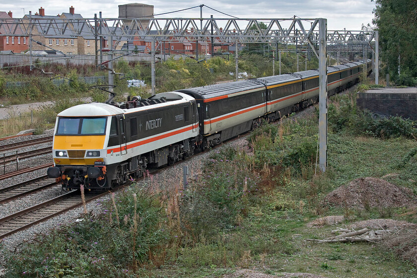 90002, 12.23 London Euston-Manchester Piccadilly (1Z94, 3L), site of Roade station 
 90002 'Wolf of Badenoch' returns from London working the 12.23 Euston to Manchester LSL relief service and is seen passing Roade taken from the locally named Gravel bridge. On the day of the Queen's funeral, it would be carrying mourners back from the capital many of whom will have been in the long and winding queue of people wishing to pay their respects whilst she laid in state in Westminster Hall. With Avanti West Coast still operating a slashed service with up to a third of their services cancelled with them blaming their staff for not working overtime other operators such as LSL saw an opportunity to operate trains and a successful move, it appears to have been. 
 Keywords: 90002 12.23 London Euston-Manchester Piccadilly 1Z94 site of Roade station Intercity swallow Wolf of Badenoch