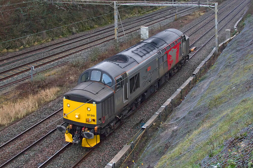 37510, 08.04 Derby RTC-Reading Triangle Sidings (0V74, 13E), A508 bridge 
 Not one of my most photographed ROG Class 37s 37510 'Orion' passes Roade, seen from the former A508 bridge. It was running as 0V74 having left Derby RTC at 08.04 ending up at Reading. I am not too sure why it was heading to Reading but given that it would be very busy over the coming few days as the starting and finishing point for most GWML trains due to the closure of Paddington it could be associated with this? 
 Keywords: Orion 37510 08.04 Derby RTC-Reading Triangle Sidings 0V74 A508 bridge ROG Rail Operations Group