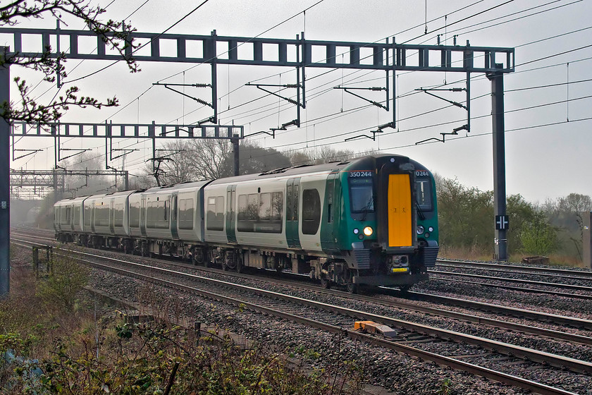 350244, LN 06.24 London Euston-Birmingham New Street (2U23, 7L), Ashton Road bridge 
 As the morning mist begins to clear, 350244 passes between Ashton and Roade on the WCML just south of Northampton with the 06.24 Euston to Crewe. Again, the new livery of these class 350 units does not look good in these dull conditions (or any condition for that matter!). 
 Keywords: 35024 06.24 London Euston-Birmingham New Street 2U23 Ashton Road bridge