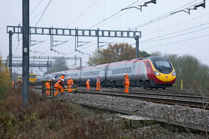 Class 390, VT 12.17 London Euston-Manchester Piccadilly (1H08), track workers on up & down slow lines, Ashton Roade bridge 
 With an acknowledging wave from one of the track workers, the 1H08 12.17 Euston to Manchester Pendolino passes a worksite between Roade and Ashton. With the up and down slow lines closed and in possession the fast lines were very much still in operation with trains at full line speed. 
 Keywords: Class 390 12.17 London Euston-Manchester Piccadilly 1H08 trackworkers on up & down slow lines Ashton Roade bridge Virgin Pendolino