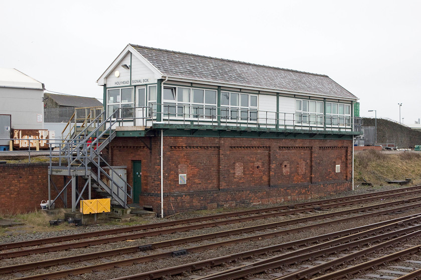 Holyhead Signal Box (LMS, 1937) 
 Just a short distance south east of Holyhead station is the signal box just out of sight of the platforms. To take this picture I stood on my short stool, looking over a wall on a busy roundabout getting some strange looks from the normals! Holyhead signal box was constructed by the LMS in 1937. It's a type 37 box that was built to replace five existing boxes. It has undergone a number of changes over time and has been modernised in recent years with horrible galvanised steel steps, UPVC cladding and windows. 
 Keywords: Holyhead Signal Box